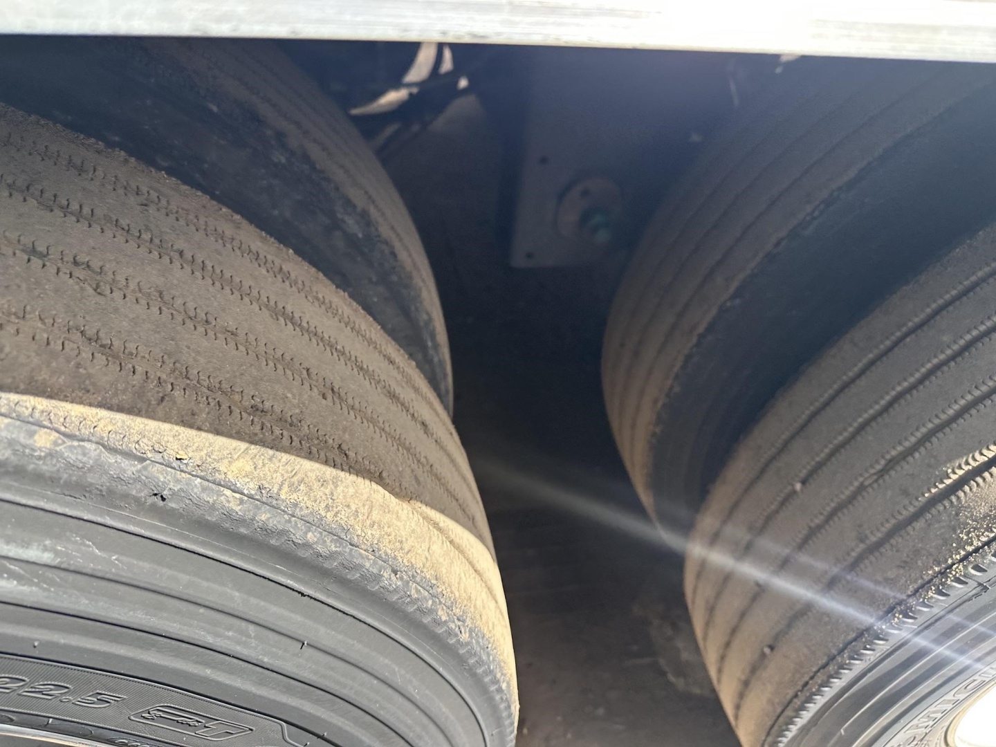 Trailer dual rear tires in a reefer unit showing tread and wheel area under a Utility 3000R trailer, with visible sidewall markings and wheel wells.