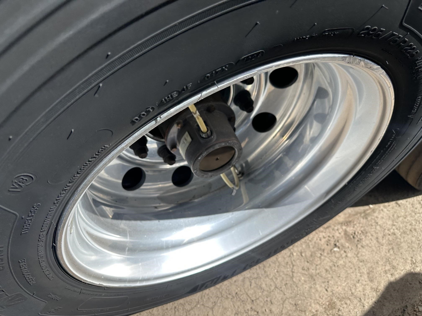 Trailer wheel close-up showing polished aluminum rim, black tire, and lug nut hub; part of a 2022 Utility 3000R reefer trailer.