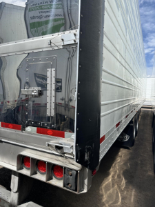 Trailer rear corner of a 2022 Utility 3000R reefer trailer showing metal panels, rear door, and triple taillight cluster.