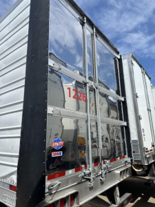 Trailer rear showing aluminum cargo doors, latching hardware, reflective tape, Utility 3000R logo sticker, and red VIN-like number 1226 on the door panel.