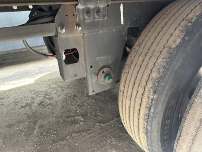 Trailer rear undercarriage showingSuspension frame and dual tire with ribbed tire tread, green valve cap, and wiring harness near the leaf spring in a Utility 3000R reefer trailer.