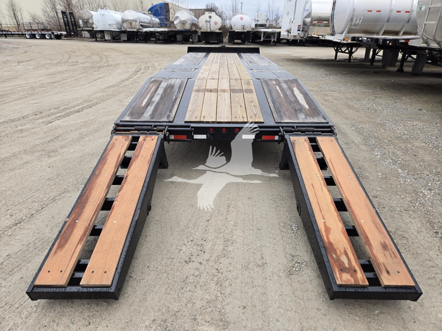 Trailer deck with wooden planks and steel frame, long flatbed with tandem wheel area visible in background.