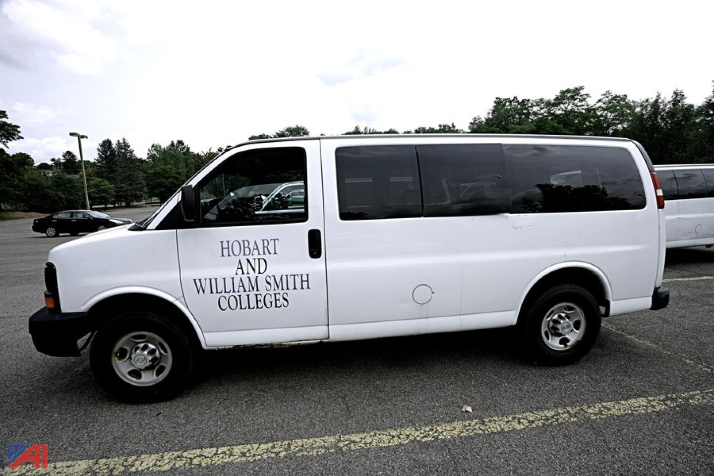 Chevrolet Express 2500 extended passenger van side view with Hobart and William Smith Colleges logo on front door, white exterior, black tinted windows.