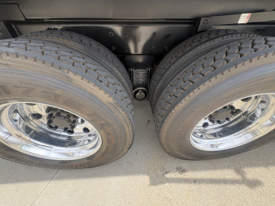 Dual rear axles with suspension and tires visible, metal leaf springs, and a central drive component between wheels.