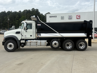 Dump truck side view showing white cab and black dump bed with chrome fuel tanks and multiple axles, Mack GR84F 6x4 chassis.