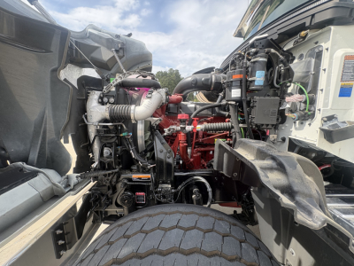 Mack GR84F engine bay view showing diesel engine components, hoses, and wiring with exposed air intake and fluid reservoirs.