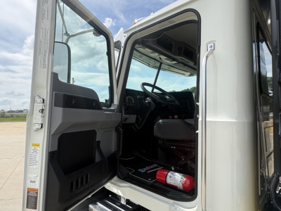 Mack GR84F truck cab with open door showing steering wheel and interior details, fire extinguisher visible on floor.