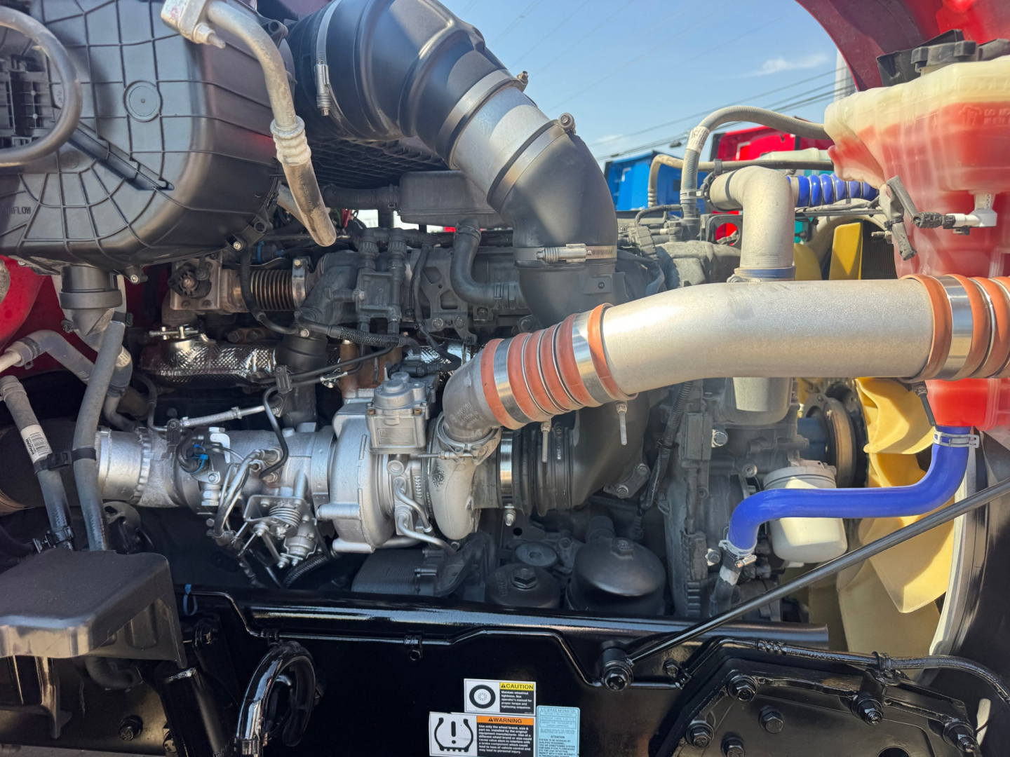 Kenworth T680 engine bay showing intake hoses, turbocharger, intercooler piping, and diesel engine components
