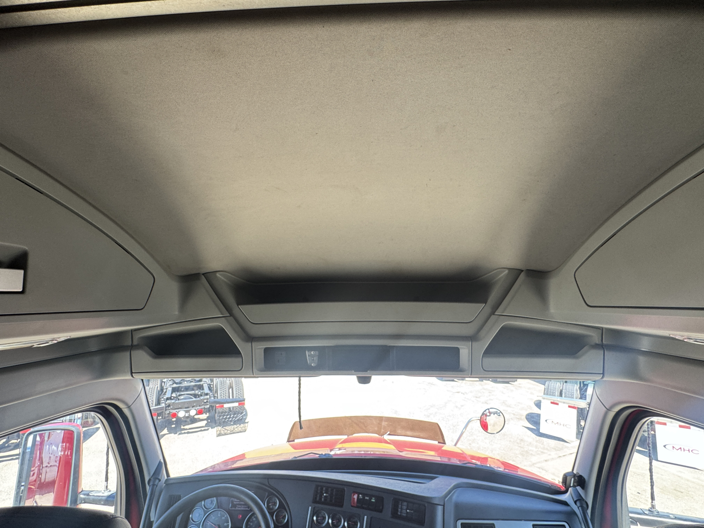 Cab interior of a 2022 Kenworth T680 truck showing the overhead headliner and sun visors.
