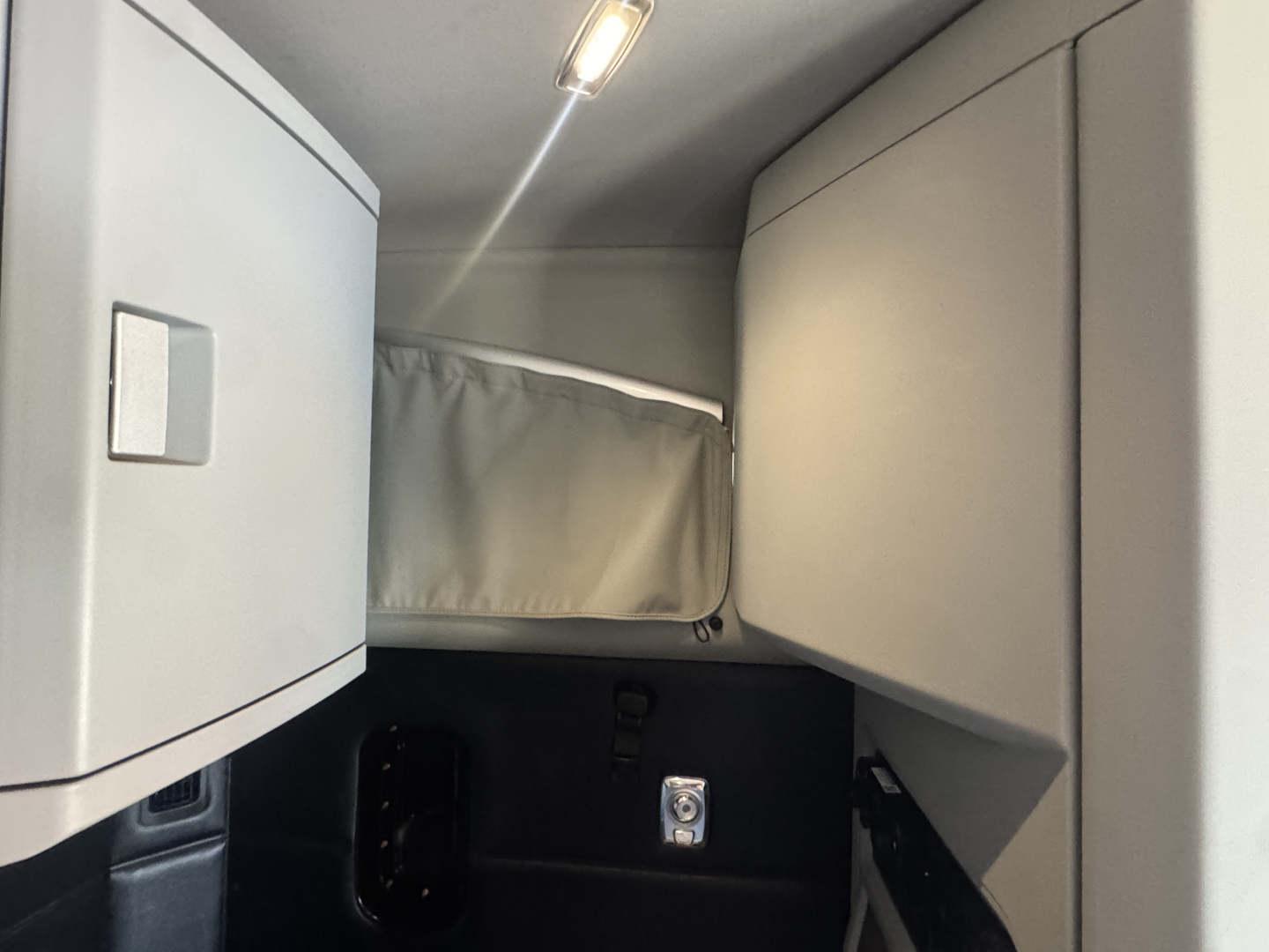 Kenworth T680 sleeper cab interior hatch area with overhead storage and window curtain visible