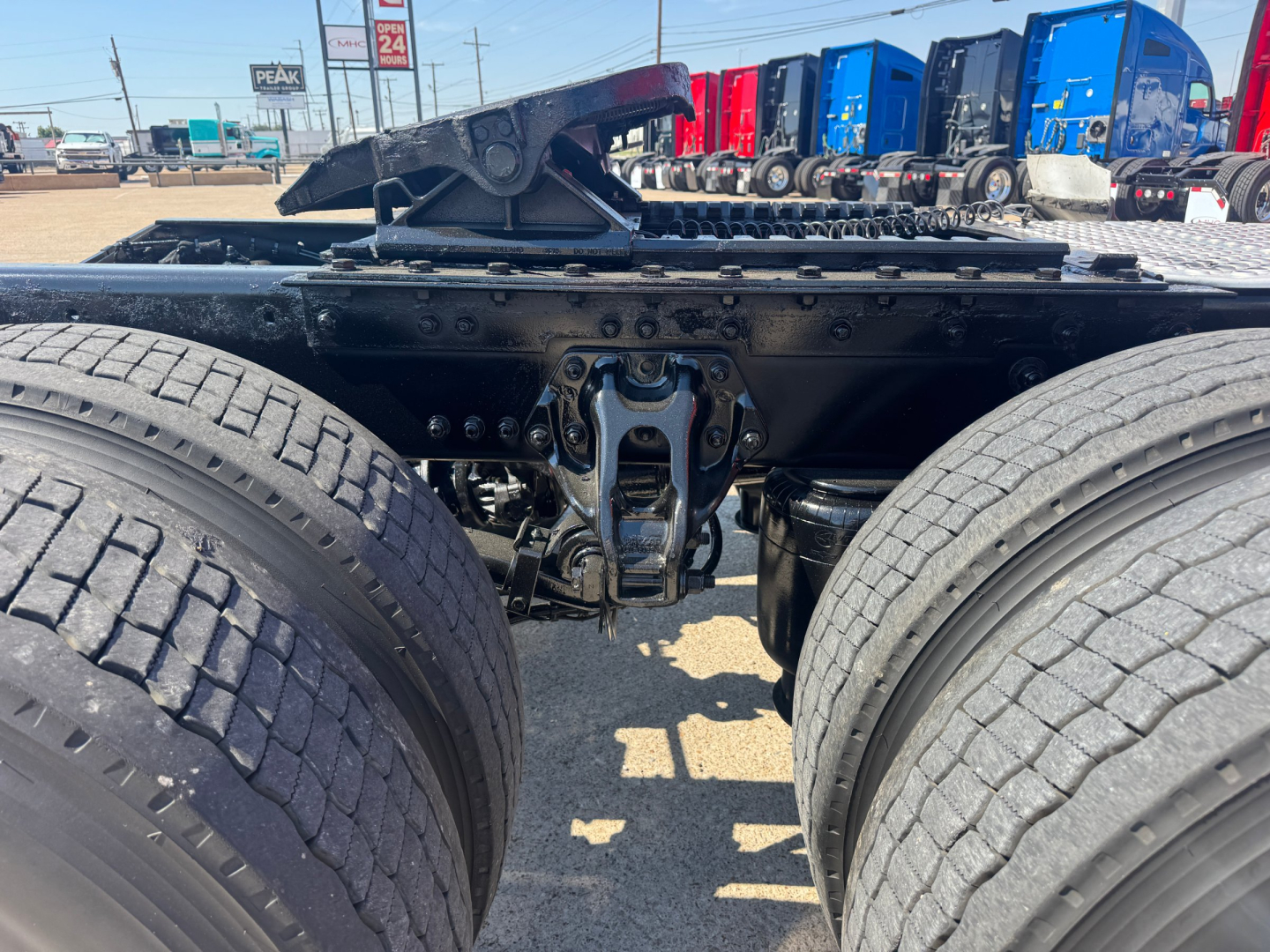 Rear view of a 2022 Kenworth T680 chassis showing dual rear axles and fifth-wheel mount with visible frame, suspension components, and tires.