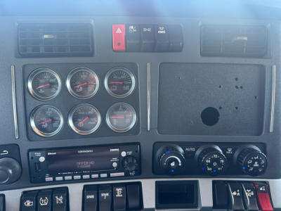 Kenworth T680 dash cluster with multiple gauges and control switches visible; center console features Kenworth radio and climate controls.