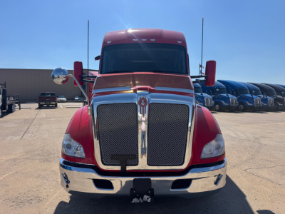 Front view of a red 2022 Kenworth T680 conventional sleeper truck with large chrome grille and bumper, windshield, and side mirrors.