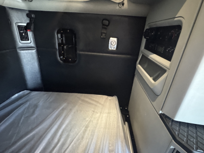 Kenworth T680 sleeper cab interior wall with panel and window controls, showing cargo area and side storage compartments.