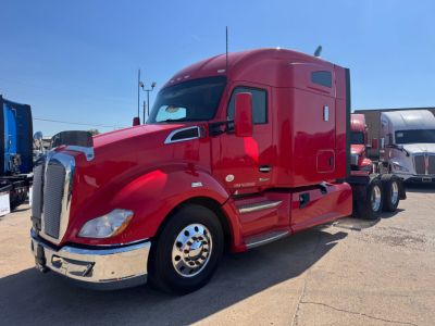 Kenworth T680 in red, side view showing cab and chrome bumper, Dual rear axles, daytime; exterior badges and mirrors visible.