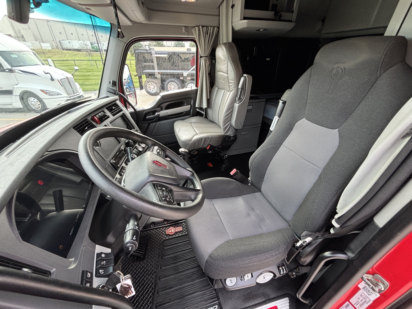 Kenworth T680 truck cab interior showing steering wheel, driver seat, and dashboard in view.