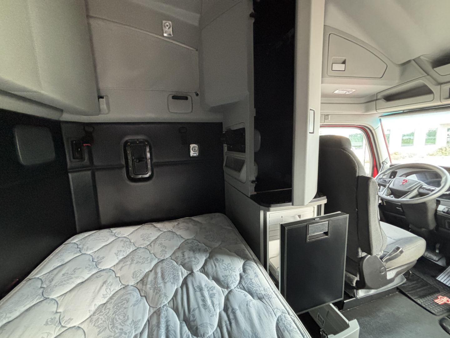 Kenworth T680 cab interior with sleeper berth and driver seat visible, storage compartments, and dashboard area.