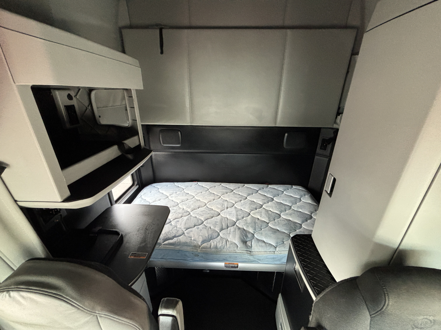 Kenworth T680 sleeper cab interior with bed platform visible and storage compartments.