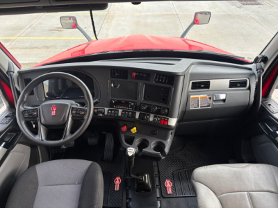 Kenworth T680 cab interior showing steering wheel, dashboard, and center console with gear shifter and controls.