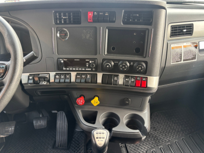 Kenworth T680 truck interior dashboard and center console with control switches, gear shifter, steering wheel, and two cup holders.