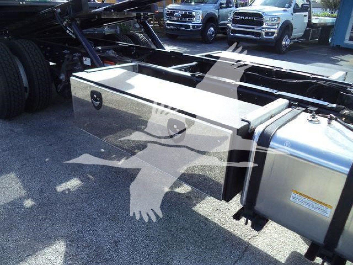 Truck chassis and fuel tank area of a 2025 Hino 268A rollback truck showing a large metallic toolbox and chassis frame.