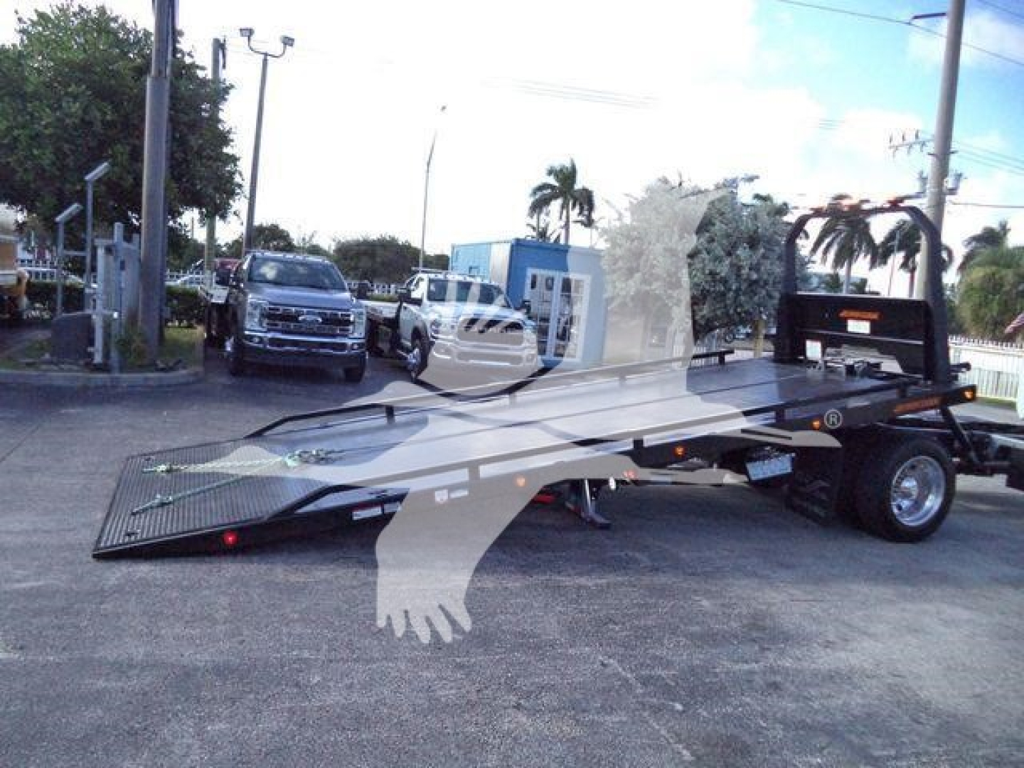 Flatbed rollback tow truck with hydraulic ramp on a lot, listed as 2025 Hino 268A.