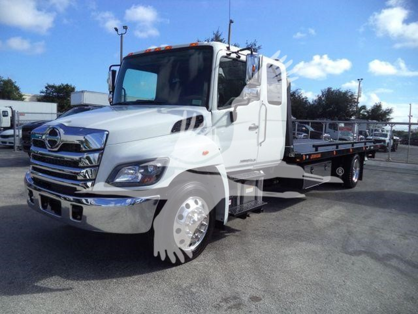 RHD truck showing 2025 Hino 268A rollback bed with chrome front grille and dual rear axles.