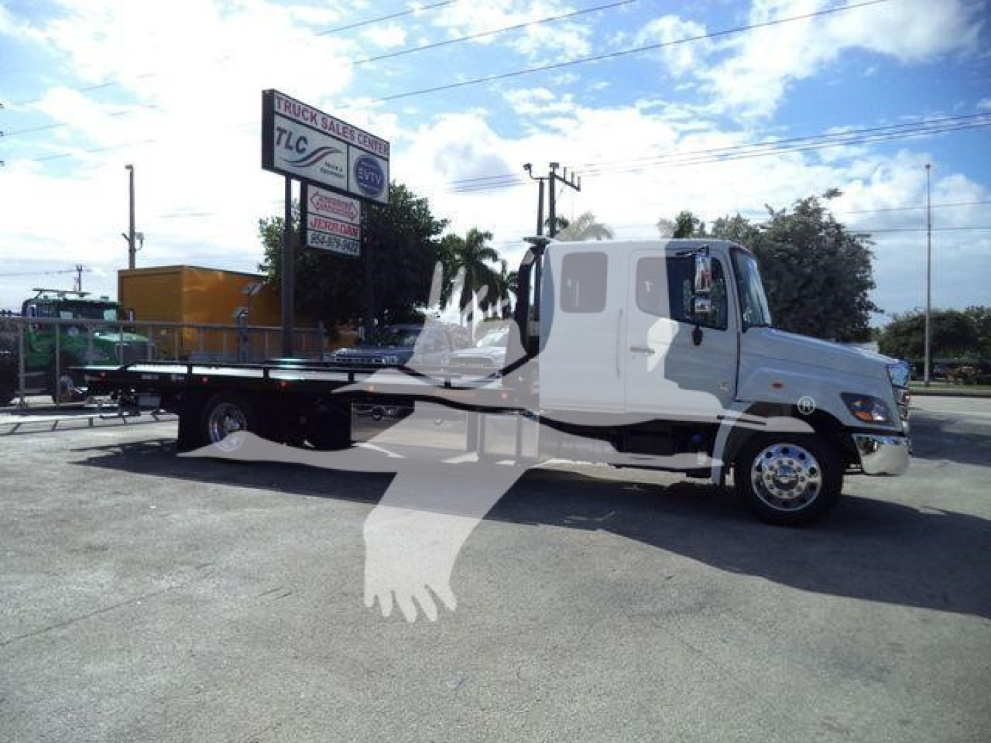 Truck shown side view of a white 2025 Hino 268A rollback tow truck with flatbed and hydraulic controls.