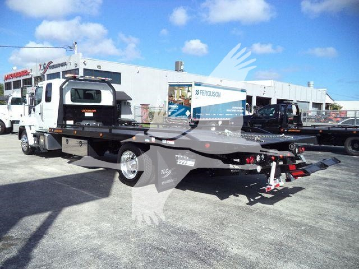 2025 Hino 268A rollback truck with flatbed and wheel lift visible, side view showing rolling bed and hydraulic components.