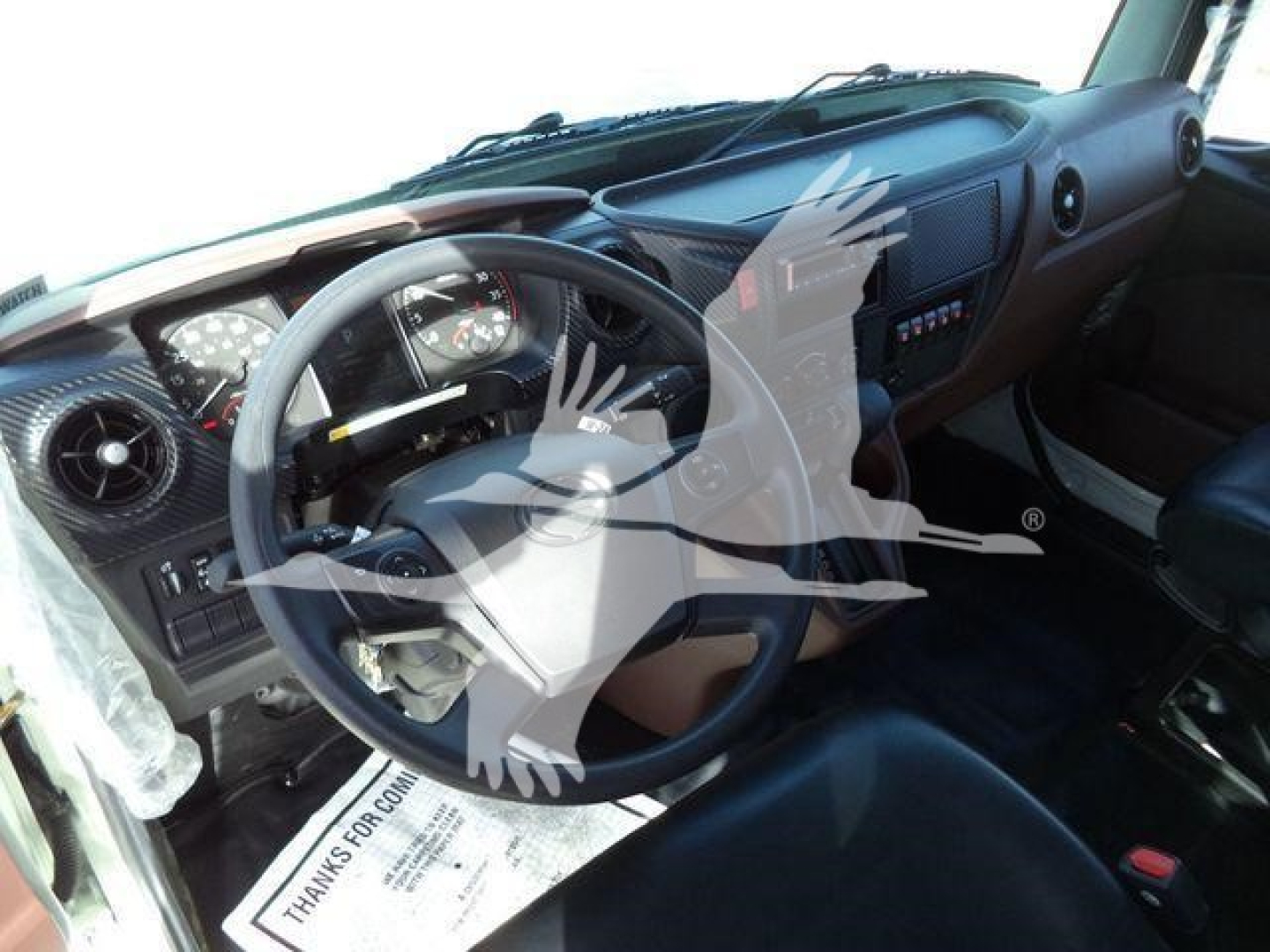 Dashboard and steering wheel view inside a 2025 Hino 268A cab showing instrument cluster and controls.