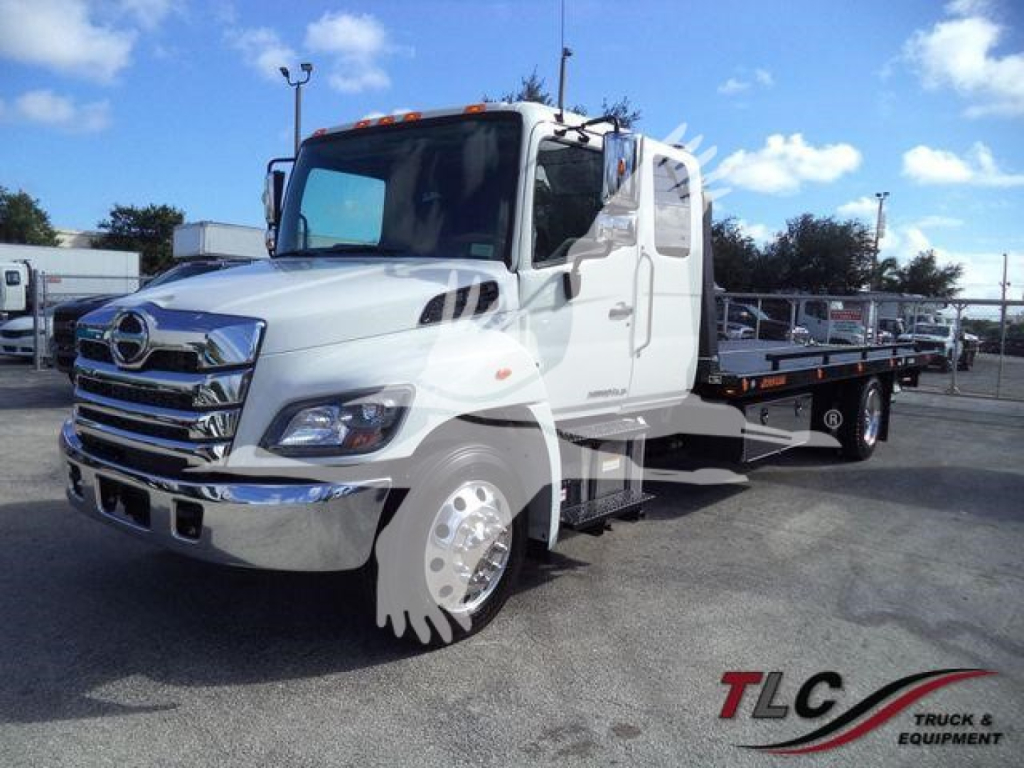 Front-left view of a white 2025 Hino 268A rollback tow truck showing chrome grille, dual rear wheels, and flatbed.