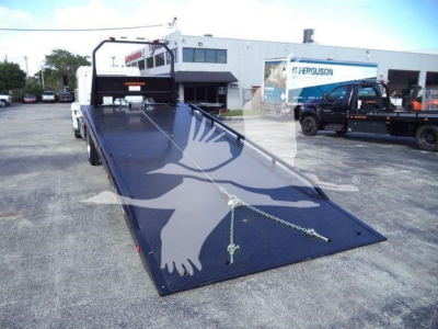 Flatbed tow truck ramp with a long blue metallic deck and winch, Hino 268A rollback truck in background.