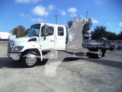 Truck image: 2025 Hino 268A rollback w/ white cab and flatbed, stock J50221FM, new/ commercial vehicle.