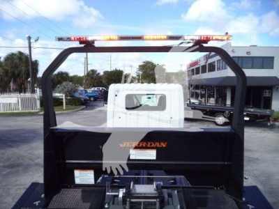 Trucks section showing the rear of a new 2025 Hino 268A rollback truck with a white cab and black Jerr-Dan body, safety lights on top, dealership lot in background.