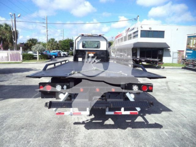 Rear view of a 2025 Hino 268A rollback truck with flatbed open, showing taillights and ramp area.
