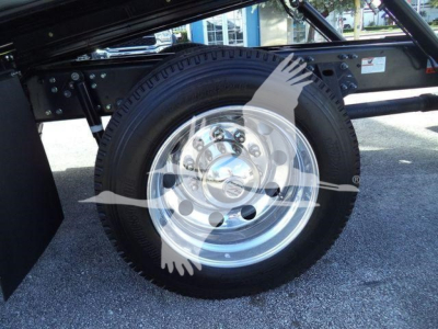 Truck wheel with polished metal hubcap and black tire on a rollback chassis, partial undercarriage visible