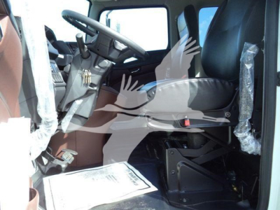 Cab interior of a new 2025 Hino 268A rollback truck showing driver seat, steering wheel, and dashboard with protective plastic on seats.