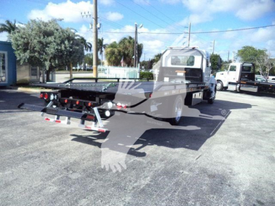 Truck bed with rollback carrier on a new Hino 268A chassis, rear view showing hydraulic ramps and lettering on the back deck.