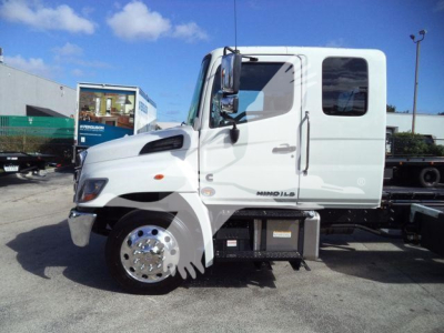 Truck cab side view showing Hino logo and wheel, with RB rollback truck chassis, fuel/air tanks, and side mirrors