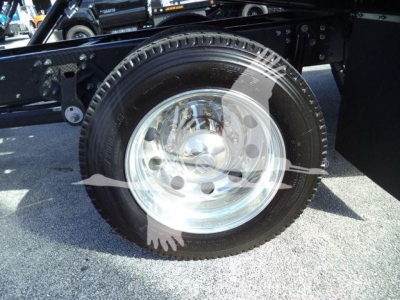 Wheel and tire close-up on a Hino 268A rollback truck showing polished steel rim and black tire.