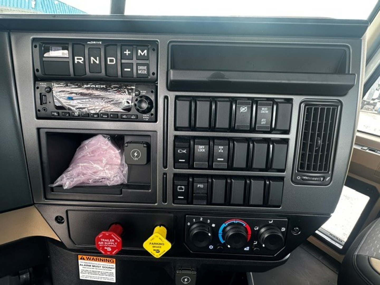 Cab console of 2027 Mack GR64F showing gear selector with R N D P plus control switches and climate dials.