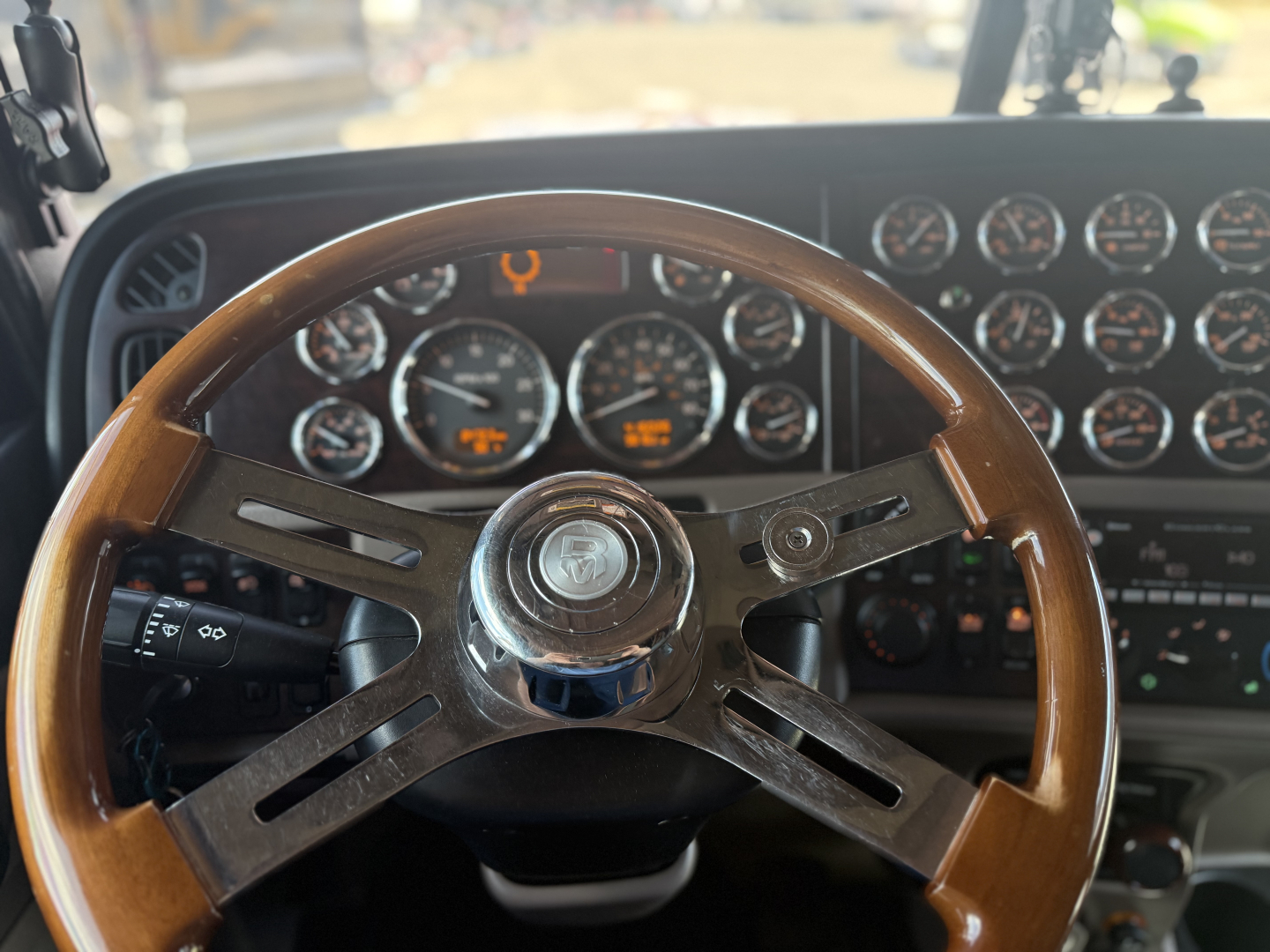Peterbilt 389 dashboard and steering wheel visible with numerous gauges in the background.