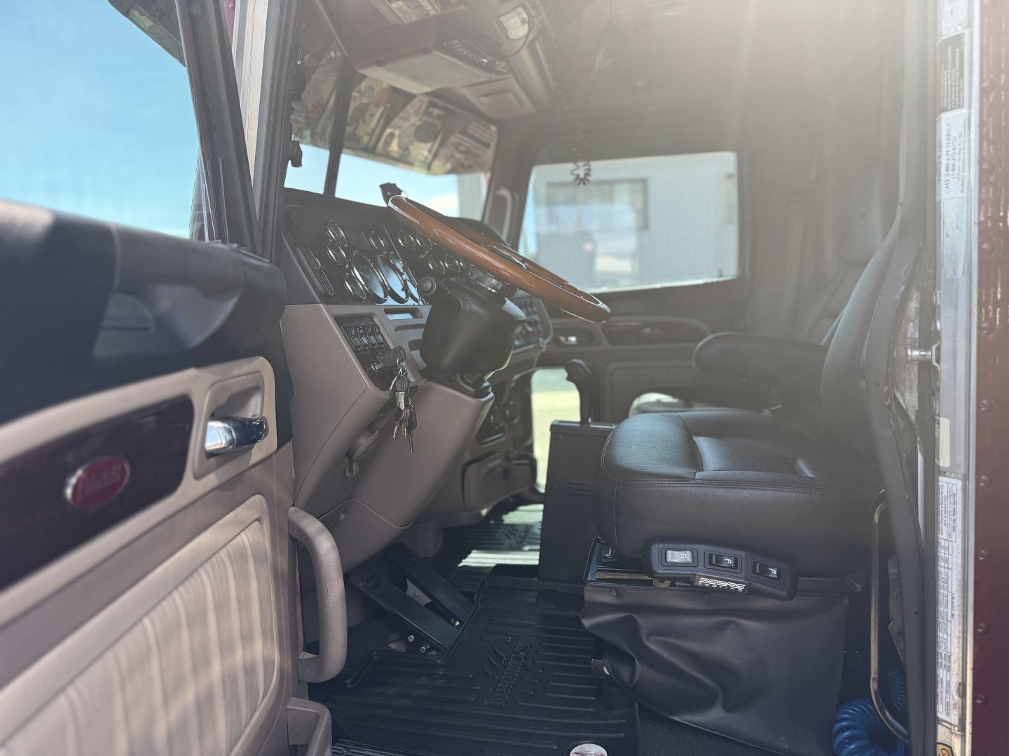 Peterbilt 389 truck interior cab view showing steering wheel, dashboard, driver's seat, and entry area.
