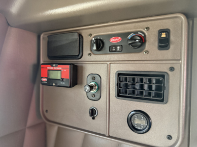 Vehicle dashboard panel with controls: 'Parker' label, two round gauges, rectangular vent, digital display, switch, and a red device labeled 'SecureIt' mounted on beige panel.