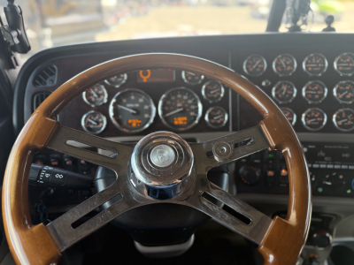 Peterbilt 389 dashboard and steering wheel visible with numerous gauges in the background.