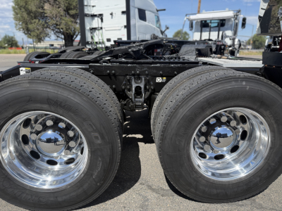 Peterbilt 389 heavy truck rear showing dual rear axles and chrome wheels; chassis and fifth wheel area visible with tires and rims.