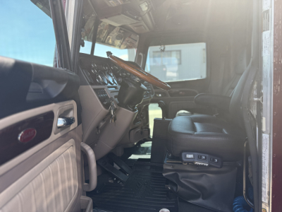 Peterbilt 389 truck interior cab view showing steering wheel, dashboard, driver's seat, and entry area.