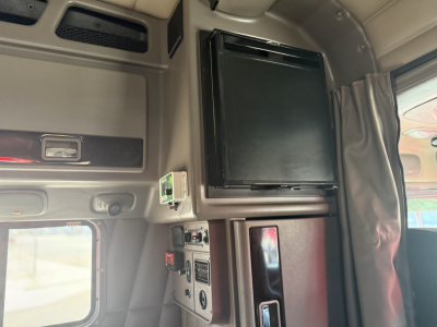 Peterbilt 389 truck interior view showing a black refrigerator or cabinet unit mounted overhead with surrounding panels and a small control panel