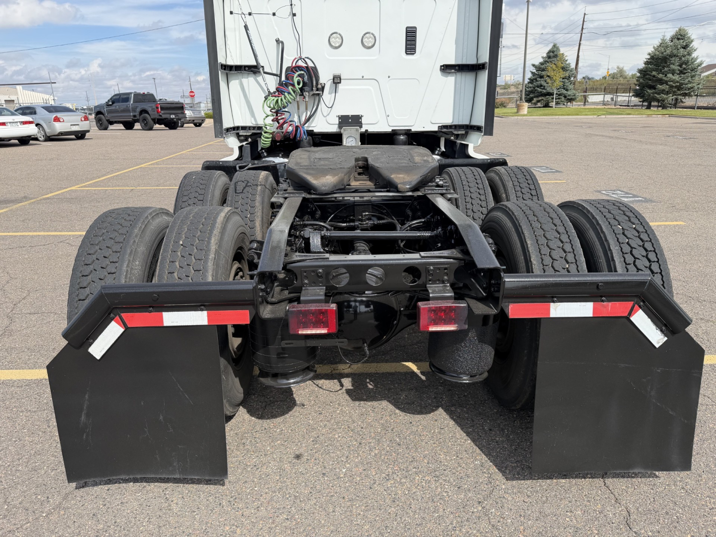 Rear view of a 2019 International LT625 truck tractor chassis with dual rear axles, dual tire sets, black mudflaps, and red/white reflective tape on the side guards.