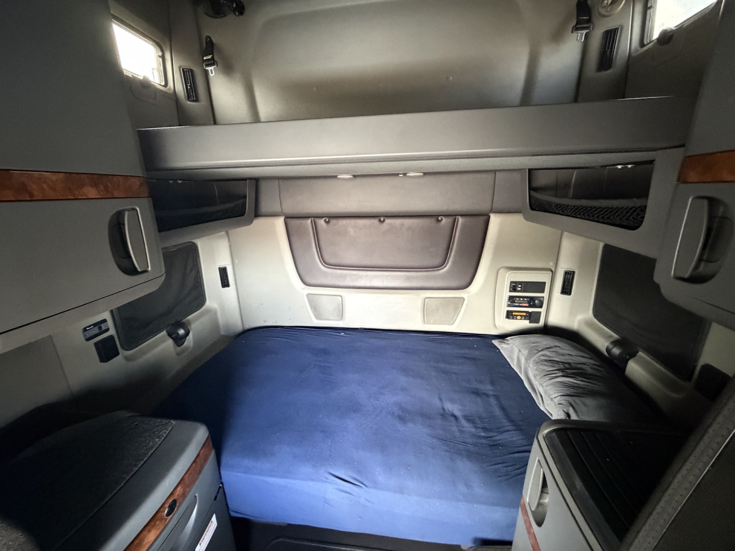 Interior bunk area of a used 2019 International LT625 sleeper cab showing a blue mattress, side cabinets, and overhead storage.
